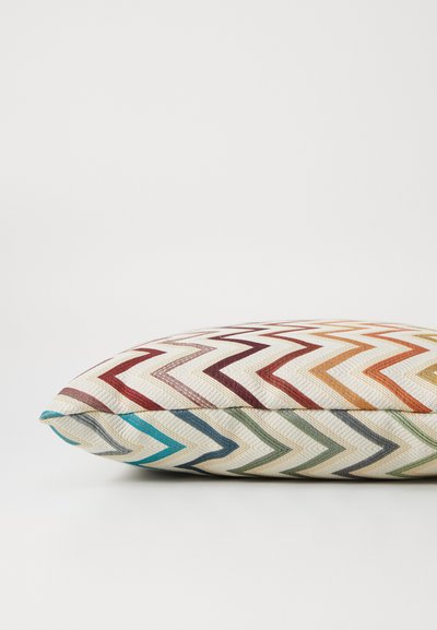 Chevron-patterned pillow with woven fabric, featuring multicolored stripes in red, yellow, blue, and green on a cream background.