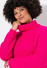 Helle pinke Rollkragensweater mit gerippter Textur und dicker Strickweise. Verfügt über lockere Ärmel und einen hohen Kragen für Wärme.