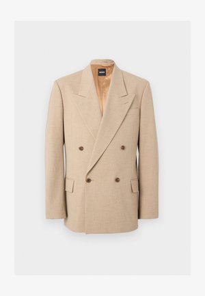 Blazer beige croisé avec larges revers, quatre boutons marron, deux poches à rabat et doublure intérieure en satin, présenté sur fond blanc.