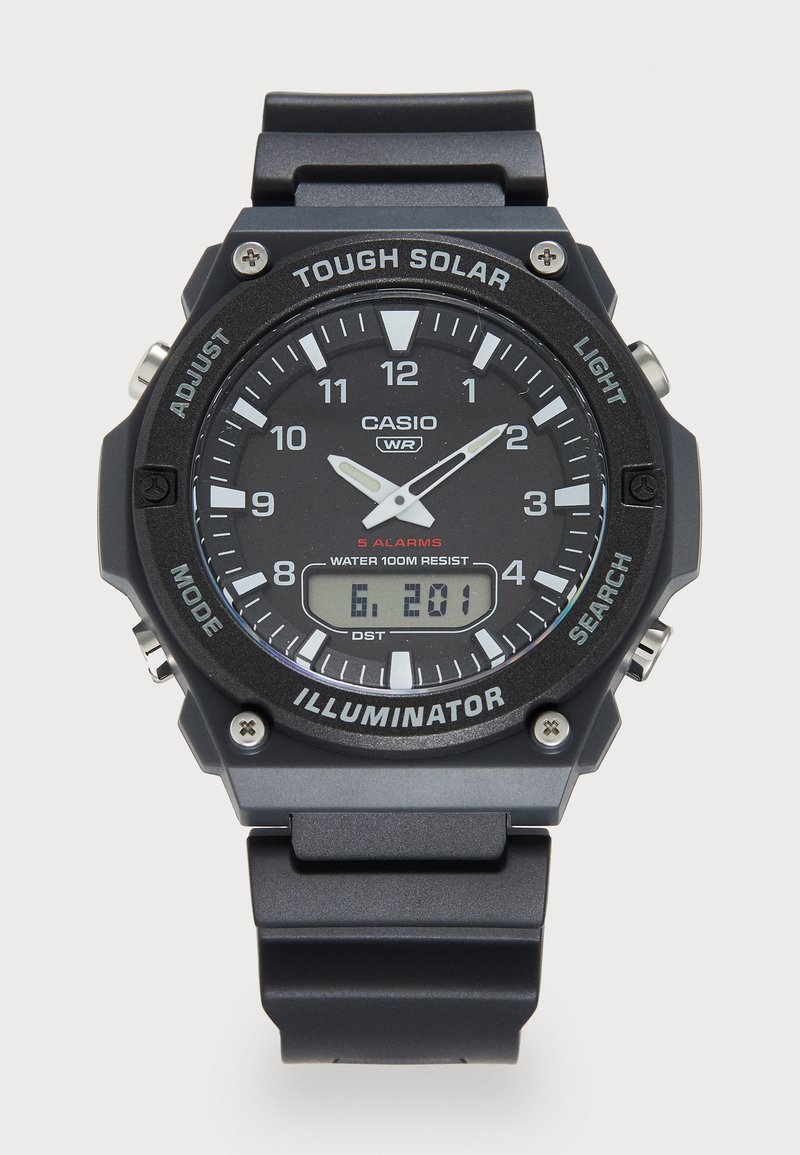 Montre numérique avec un bracelet en résine noire, un cadran rond, des aiguilles lumineuses et un affichage numérique. Les caractéristiques incluent une résistance à l'eau et plusieurs alarmes.