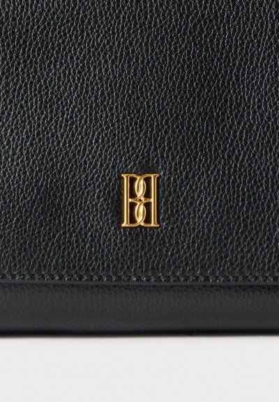 Μαύρο δερμα με υφή και διακριτική κόκκωση. Διαθέτει χρυσό μονογράμμα, τοποθετημένο στην κάτω δεξιά γωνία. Καθαρός, μοντέρνος σχεδιασμός.