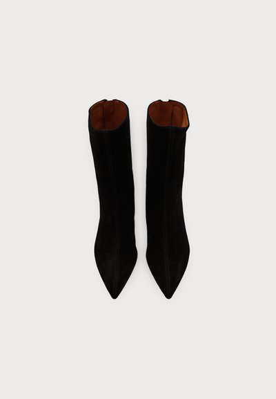 Paire de bottines en daim noir à bout pointu avec des tiges hautes et une doublure intérieure marron vue de dessus.