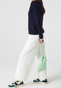 Navy sweater, white wide-leg pants, mint green drawstring bag, and green-accented sneakers. Smooth textures and contrasting colors.