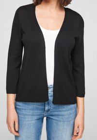 Black knitted cardigan with a V-neck, three-quarter sleeves, and open front design, paired with a white T-shirt and blue jeans.