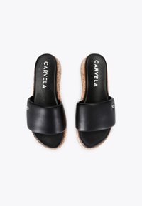 Czarne skórzane sandały na płaskiej podeszwie z szerokim paskiem, korkową podeszwą i wytłoczonym logo na wkładce. Płaski design, nowoczesna estetyka.