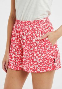 Shorts floraux rouges avec un motif de fleurs blanches, taille élastique, poches latérales, tissu léger et coupe décontractée pour le confort.