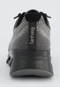 Chaussure de sport grise avec une tige en tissu texturé, un design à motifs, des accents noirs et une semelle rembourrée avec un logo distinct au niveau du talon.
