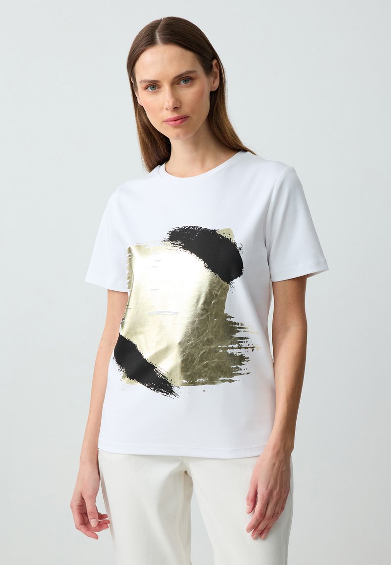 T-shirt bianca a maniche corte con un design a strisce oro e nero sul davanti. Vestibilità rilassata con materiale in cotone morbido.