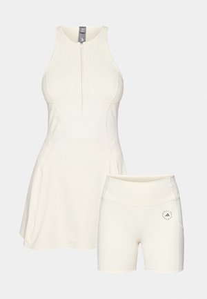 Robe de sport blanche à col montant et fermeture éclair, accompagnée de shorts ajustés assortis avec un imprimé logo sur la cuisse.