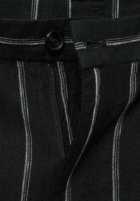 Țesătură neagră cu dungi verticale albe; dispune de un sistem de închidere cu buton și fermoar. Material texturat din in; detalii vizibile de cusătură.
