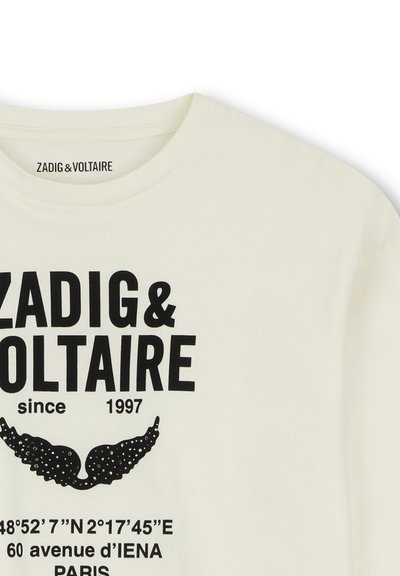 Λευκό πουκάμισο με μαύρο κείμενο που γράφει Zadig & Voltaire since 1997, συντεταγμένες 48°52'7"E, και 60 avenue d'IENA Paris, συν γραφικό φτερού.