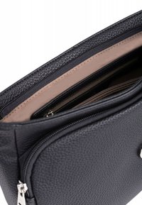 Borsa in pelle nera con finitura testurizzata, dotata di apertura con zip, interno beige e tasca con zip aggiuntiva per l'organizzazione.