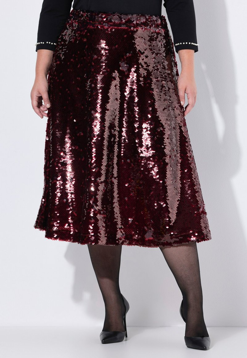 Gonna bordeaux con paillettes, design svasato e lunghezza al ginocchio. Abbinata a collant neri trasparenti e scarpe con tacco nero.