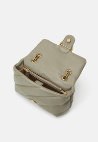Lysegrønn skinnveske med quiltet design, som har detaljer i gull, trykknapplukking og en glidelåsinnvendig rom.