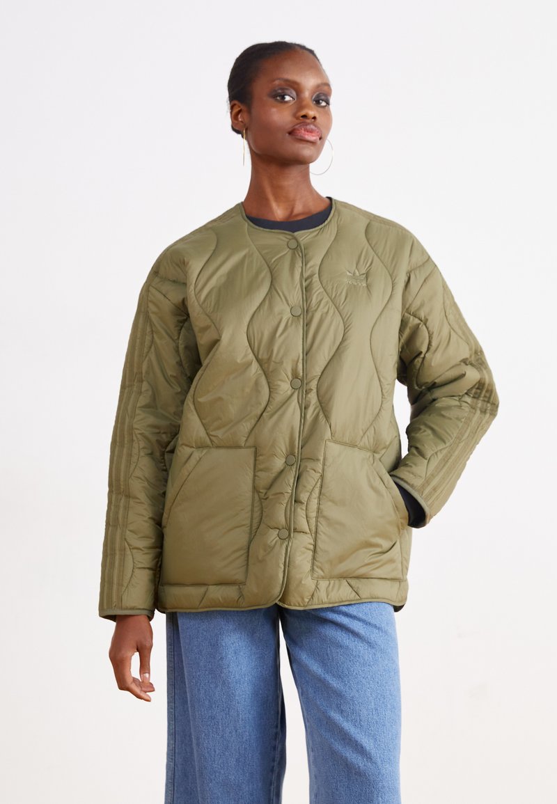 Zelenkasto olivno prešit jakna s zaobljenim ovratnikom, sprednjimi pritisnimi gumbi in dvema velikima žepoma. Teksturiran geometrijski vzorec po celotni površini.