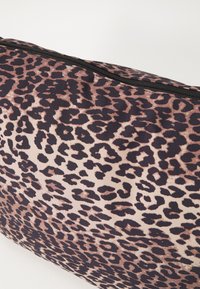 Lapsa ar leoparda rakstu, kas izgatavota no krēmkrāsas un tumši brūnas nokrāsas sajaukuma. Iespējo kontrastējoša rāvējslēdzēja aizdare un teksturēta auduma virsma.