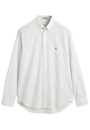 Valkoinen nappipaita, jossa on pieniä sinisiä pilkkuja. Pitkät hihat, pyöreä helma, etutasku, jossa on logo vasemmalla puolella. Puuvillakangasta.