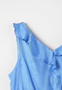 Blå ärmlös topp med en volangkrage, med en slät tygtextur och en lätt glans. Enkelt design utan extra mönster.