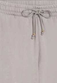 Light gray sweatpants with an elastic waistband, drawstring fastener, and gold-accented tips; soft, smooth texture.