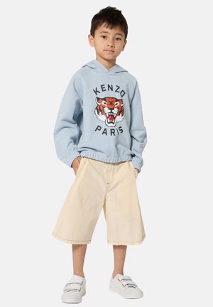 Sweat à capuche bleu clair avec un graphisme de tigre et le texte "KENZO PARIS", associé à un short beige mi-long et des baskets blanches à scratchs.