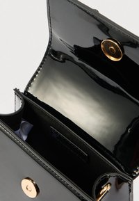 Geantă din piele lac neagră, cu finisaj lucios. Are închidere magnetică, compartimente interioare și un buton decorativ auriu.