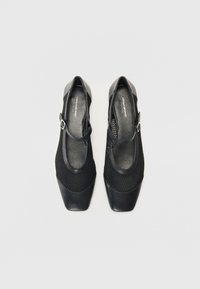 Black shoes with a mesh upper, square toe, and a strap featuring a buckle. Soft texture with pronounced accents. Suitable for casual wear.