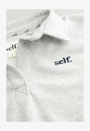 Graues Poloshirt mit strukturiertem Finish, ausgestattet mit einem spitzen Kragen und einem gestickten "self."-Logo in Marineblau. Größenschild innen sichtbar.