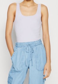 Light lavender ribbed tank top with a square neckline paired with light blue, loose-fitting cargo pants featuring an elastic waistband and pockets.