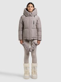 Let jakke i lysegrå med høj krave, lynlåslomme og snøre. Båret med matchende grå leggings og hvide sne-støvler.