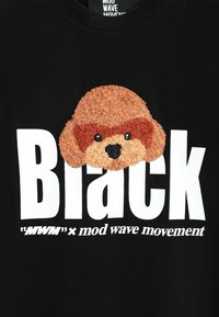 Camiseta de algodón negra con un diseño texturizado de un perro marrón con ojos negros. Gran texto blanco que dice "Black" y la marca debajo.