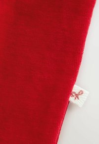 Tessuto rosso con una superficie liscia, caratterizzato da un piccolo etichetta bianca con un logo marrone. Il bordo è rifinito in modo ordinato.