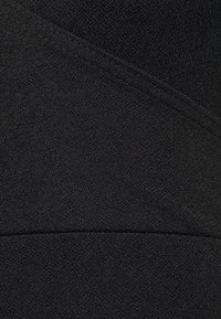 Tecido preto com uma superfície texturizada e costuras diagonais. Liso e elástico, com um brilho subtil, criando uma aparência em camadas.