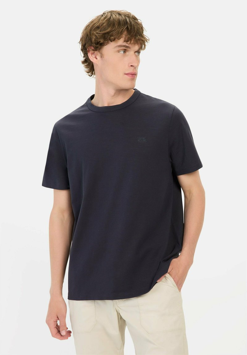 Marineblauwe t-shirt met korte mouwen en een ronde halslijn, gemaakt van zachte katoen, met een subtiele logo op de borst. Soepele textuur, ontspannen pasvorm.