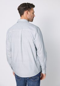 Lichtblauw geruit overhemd met knopen, lange mouwen, kraag en een achterpasdetail, gecombineerd met blauwe spijkerbroek.