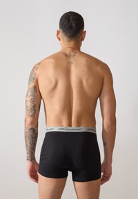 Fekete boxer alsónadrág szürke rugalmas derékkal, amely jellegzetes mintával díszített. Az anyag simának tűnik, testhezálló kialakítással.