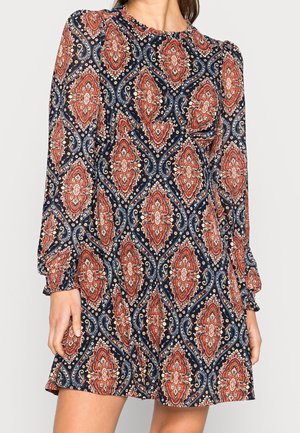 Langärmeliges Kleid in Marineblau mit einem Paisleymuster in Rot, Weiß und Creme. Fließender Stoff mit Raffungen am Ausschnitt und an den Ärmeln.