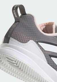 Buty sportowe z szarym siateczkowym wierzchem, różowym wnętrzem i białą gumową podeszwą. Charakteryzują się wzorzystą strukturą i pętelką na pięcie.