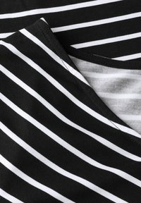 Schwarz-weiß gestreifter Stoff, der ein V-Ausschnitt-Design mit weicher, glatter Textur zeigt. Ordentliche Nähte entlang der Kanten.