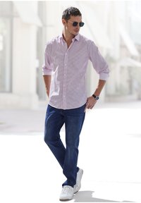 Rot-weiß kariertes Hemd mit Knopfleiste, kombiniert mit blauen Jeans und weißen Sneakers. Sonnenbrille rundet das lässige Outfit ab.