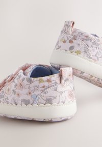 Scarpe slip-on in tessuto a motivo floreale in rosa pastello con suola bianca testurizzata e piccoli anelli sul retro per indossarle facilmente. Dettaglio con cuciture rinforzate.