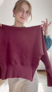 Burgunderfarbener gerippter Pullover mit lockerer Passform, weitem Ausschnitt und seitlichen Schlitzen. Das Material wirkt weich und strukturiert.