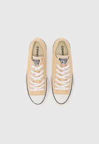 Gule lerretssko med hvite snøringer, svarte gummisåler og tåhette. Utstyrt med "CONVERSE ALL STAR" logo på tungen.