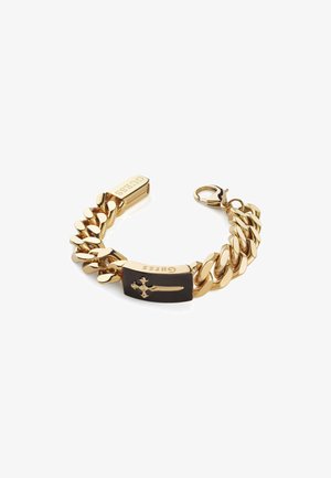 Arany színű lánc karkötő fekete téglalap alakú akcentussal, melyen kereszt design található. Biztonságos rögzítést biztosító homárkapoccsal ellátva.