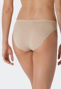 Mutande a righe beige con una consistenza liscia, vita semi-elastica e copertura completa, caratterizzate da un design senza cuciture alle aperture delle gambe.