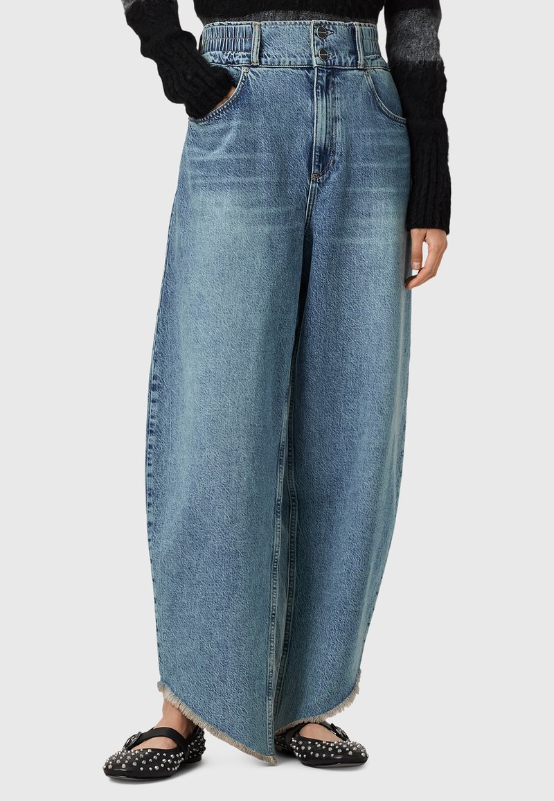 Jeans di jeans light blue a gamba larga con orlo sfilacciato, vita alta e due tasche frontali. Completati con scarpe nere con borchie.