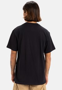 T-shirt in cotone nero con maniche corte e collo rotondo. Presenta una vestibilità rilassata. Tessuto morbido e senza motivi o dettagli visibili.