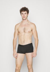 Boxer briefs neri in cotone con una vita elasticizzata che presenta un logo. Texture liscia, design aderente e copertura corta delle gambe.