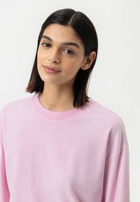 Lichtroze t-shirt met lange mouwen, een ronde halslijn en een losse pasvorm, met een soepele katoenstructuur en minimale stikdetails.