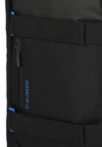 Bolsa de viaje negra de tela que cuenta con un bolsillo frontal con cremallera, correas duraderas y acentos azules. Superficie texturizada con un diseño limpio y moderno.