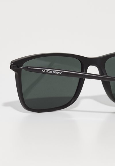 Mustad prillid tumedate roheliste läätsedega. Raam on matt ja omab elegantset disaini. Käe külje peal on valge "Giorgio Armani" logo.